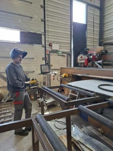 Dario, apprenti chez Métalinox, opérant une machine-outil pour le formage de pièce en acier inoxydable.