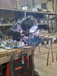 Léo, alternant en BTS, réalisant une soudure sur une pièce d'inox dans l'atelier Métalinox