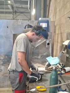 Dario apprenti chaudronnier meulant une pièce dans l'atelier Metalinox