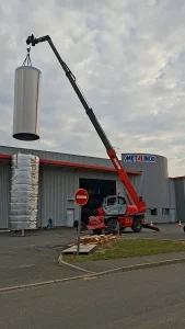 Personnel Métalinox en nacelle guidant le positionnement d'une cuve viticole.