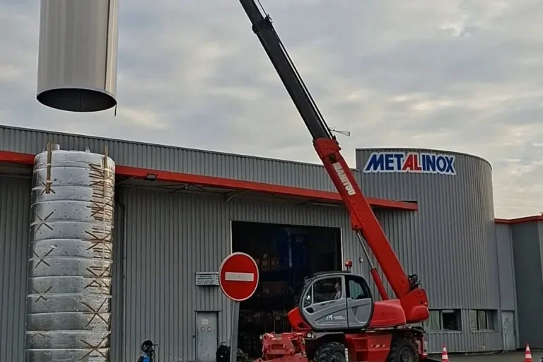 Personnel Métalinox en nacelle guidant le positionnement d'une cuve viticole.